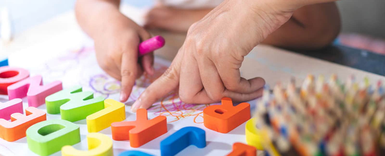 Tutor helping young student with plastic alphabet characters