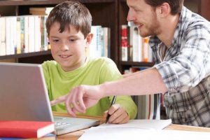 Father helping son on computer